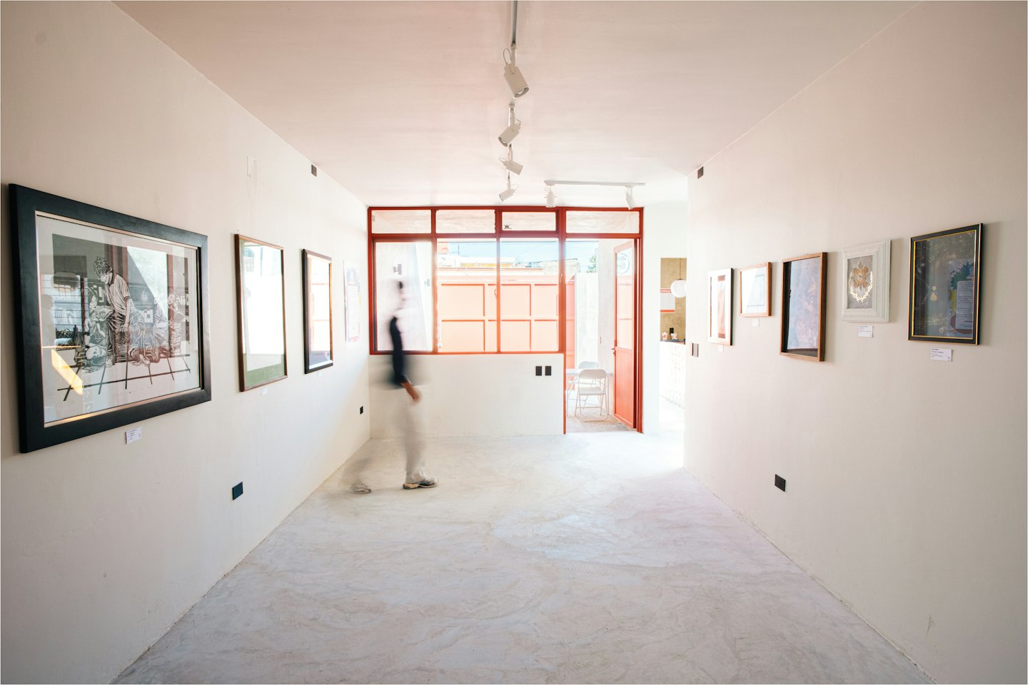 Person walking through a modern art gallery with framed artworks.